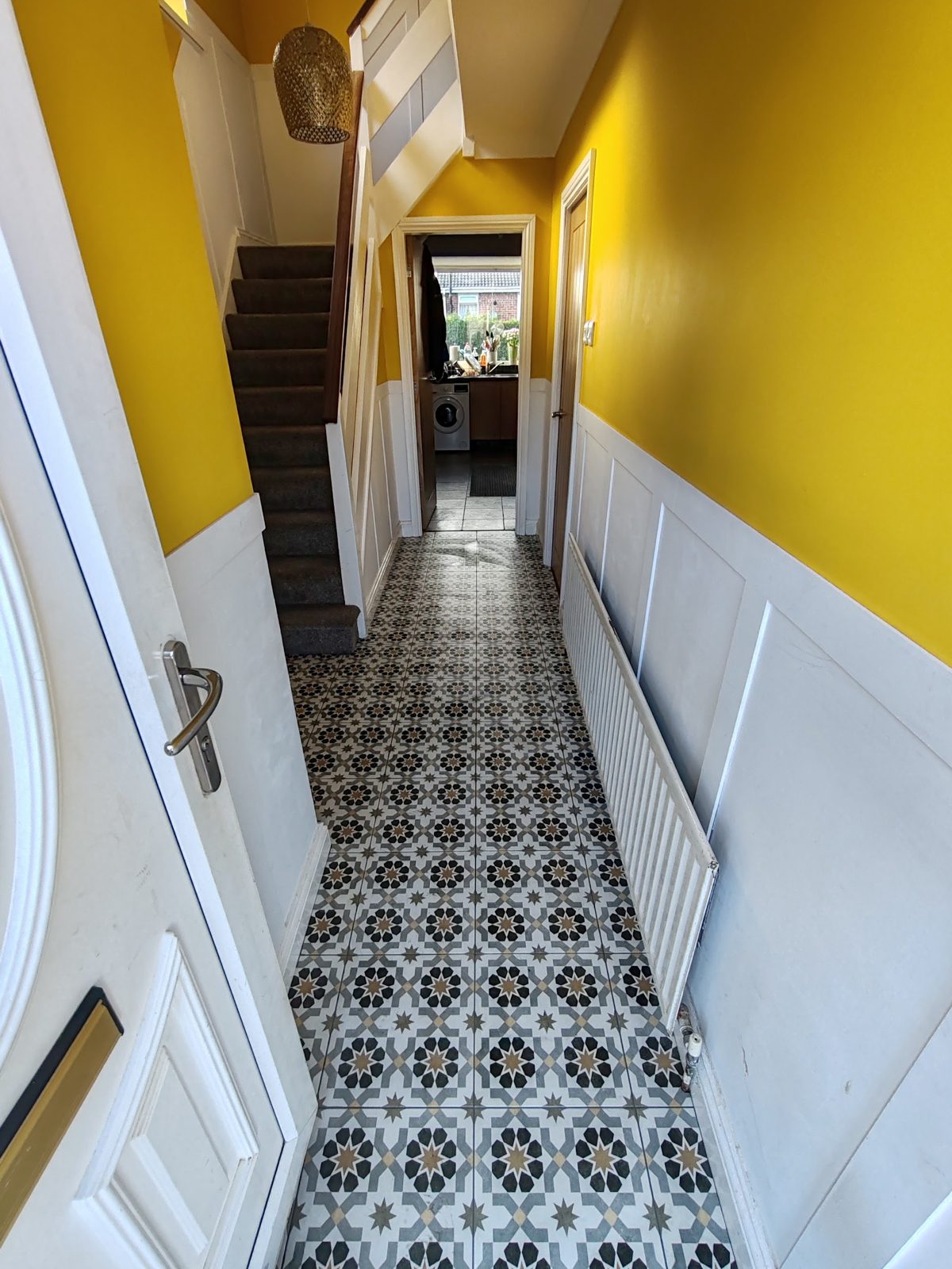 Hallway with a patterned tiled floor, yellow walls and white panelling